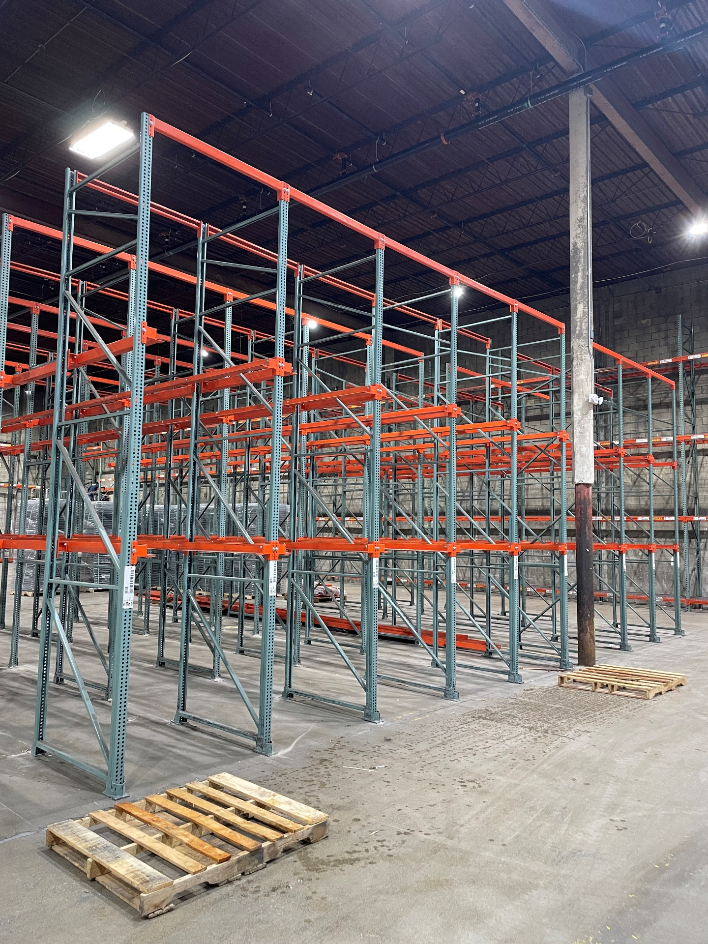 Multi-bay drive-in pallet racking with green uprights and orange beams in large warehouse buildout in Columbus OH