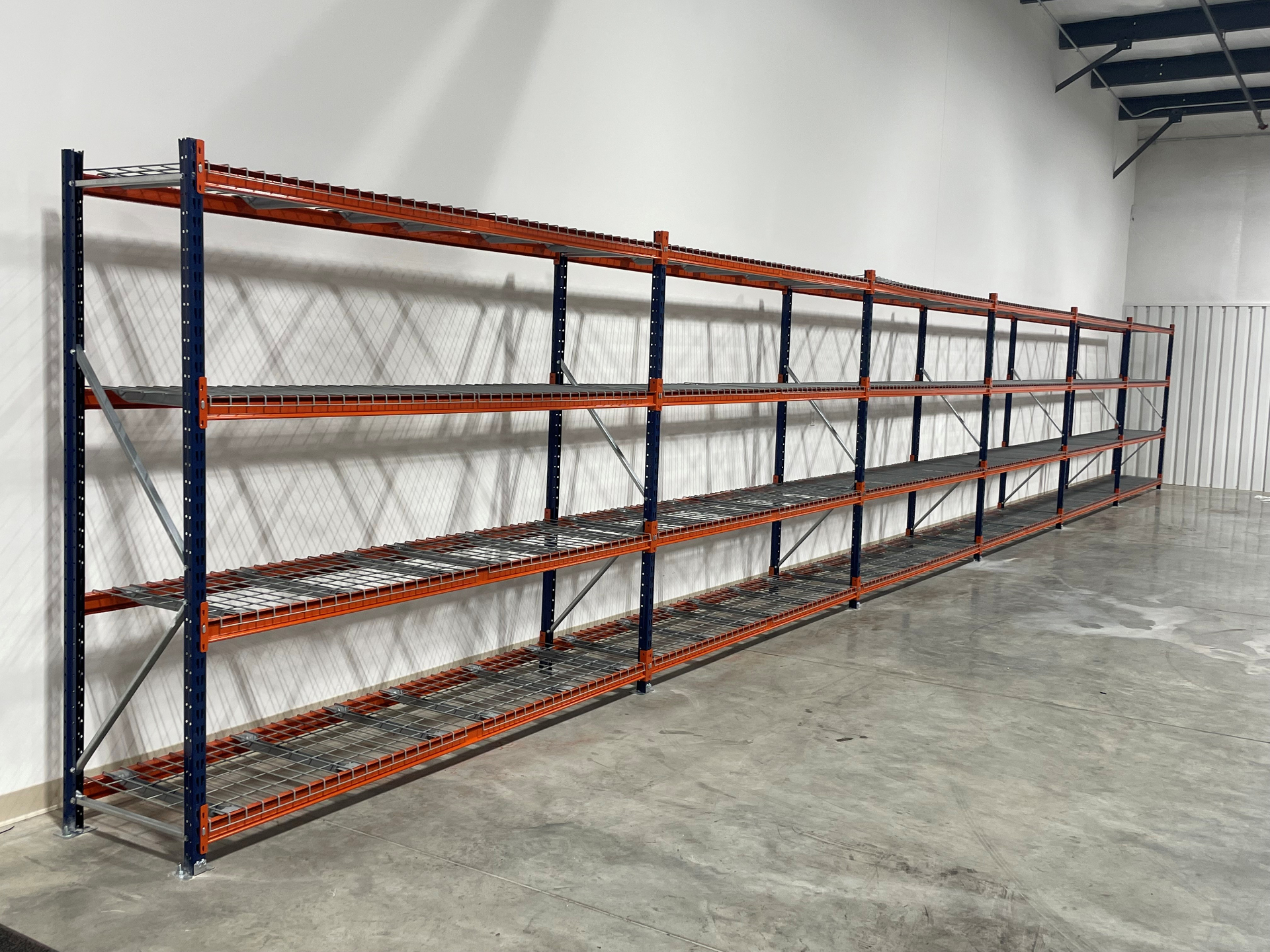 Long run of wide span shelving with wire decking and blue uprights along warehouse wall in Cincinnati OH